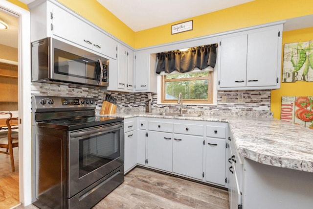 8383 N 50th St, Brown Deer, WI 53223 - kitchen with appliances with stainless steel finishes, light countertops, light wood-style flooring, backsplash, and white cabinets
