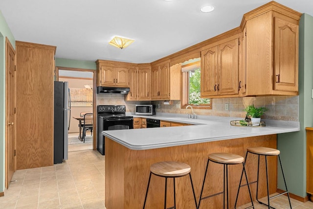 2939 W Roselawn Dr, Appleton, WI 54914 - kitchen with under cabinet range hood, black appliances, a peninsula, light countertops, and decorative backsplash