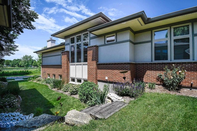 6846 Frank Lloyd Wright Ave, Middleton, WI 53562 - view of property exterior with brick siding, a lawn, stucco siding, and a chimney