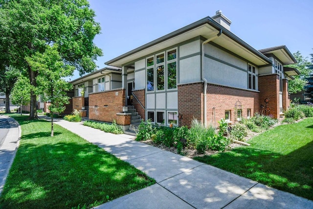 6846 Frank Lloyd Wright Ave, Middleton, WI 53562 - view of home's exterior with brick siding, a chimney, stucco siding, and a yard