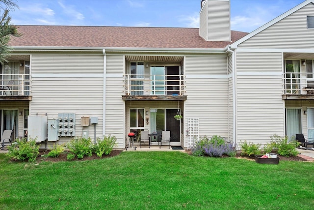 847 W Puetz Rd, Oak Creek, WI 53154 - back of house featuring a balcony, a yard, a chimney, and a shingled roof