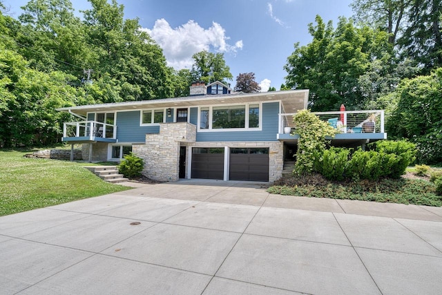 915 Mariane Ter, Lake Geneva, WI 53147 - view of front of property with a balcony, a garage, concrete driveway, a front lawn, and stone siding