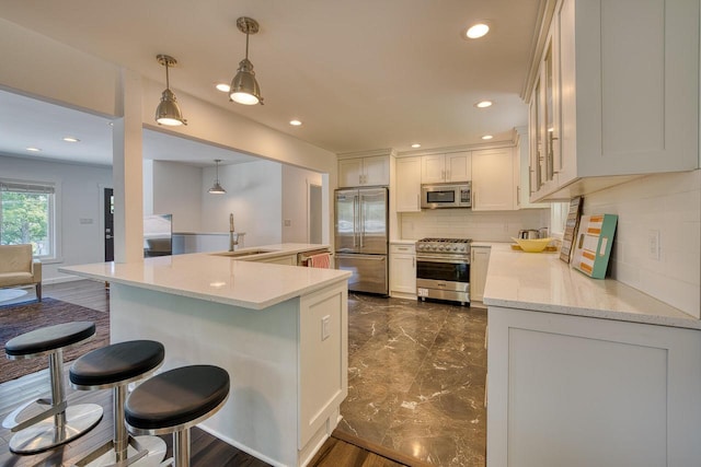 915 Mariane Ter, Lake Geneva, WI 53147 - kitchen with high end appliances, backsplash, a breakfast bar, dark marble finish floors, and recessed lighting