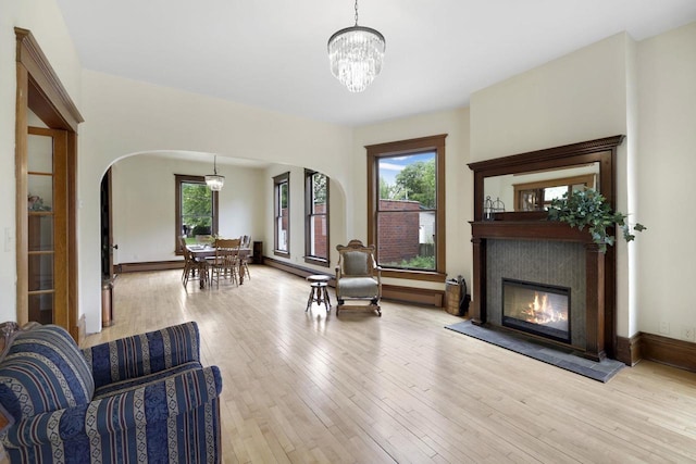 205 W Main St, Weyauwega, WI 54983 - living room with arched walkways, a chandelier, light wood-style floors, and a glass covered fireplace