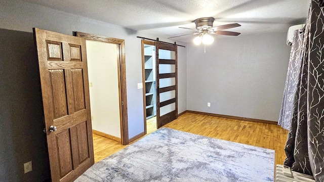 553 W 17th Ave, Oshkosh, WI 54902 - empty room with a barn door, a ceiling fan, light wood finished floors, and a textured ceiling