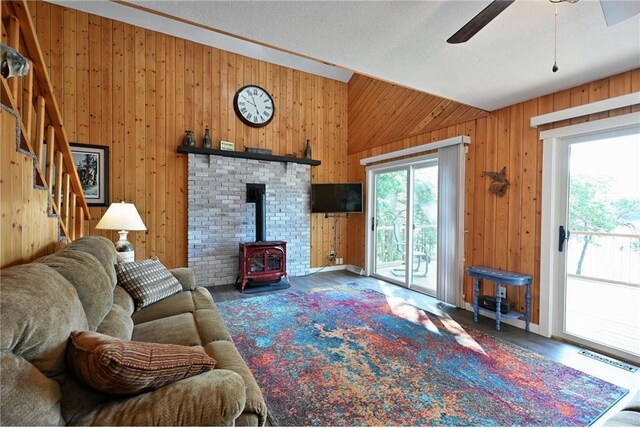33516 No Mans Trl, Minong, WI 54859 - living area featuring wooden walls, a wood stove, a ceiling fan, vaulted ceiling, and wood finished floors