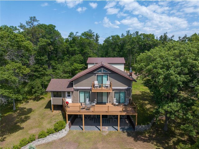 33516 No Mans Trl, Minong, WI 54859 - back of property with a balcony, a wooden deck, a forest view, and a lawn