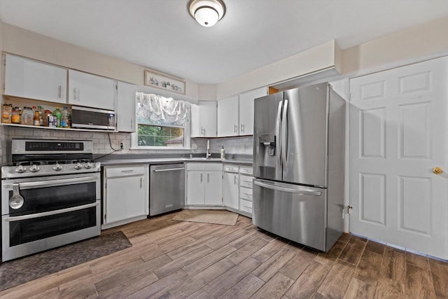 8088 N 65th St, Brown Deer, WI 53223 - kitchen with stainless steel appliances, white cabinets, light wood finished floors, and backsplash