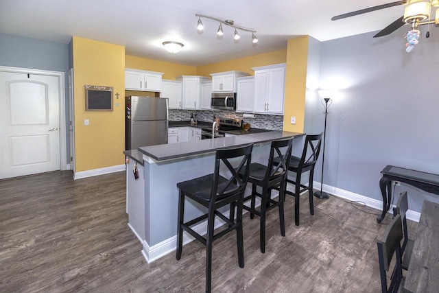N165W20576 Berry Patch Rd Unit 702, Jackson, WI 53037 - kitchen with stainless steel appliances, dark countertops, a peninsula, white cabinets, and dark wood-style flooring