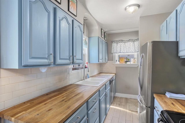 902 E Fremont St, Appleton, WI 54915 - kitchen with butcher block countertops, blue cabinetry, appliances with stainless steel finishes, and tasteful backsplash
