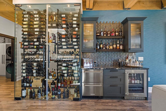 N52W35002 Lake Dr Unit 302, Okauchee, WI 53069 - wine area with beverage cooler, estacked washer and dryer, bar with sink, and wood finished floors