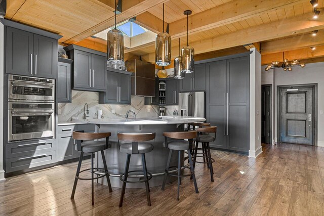 N52W35002 Lake Dr Unit 302, Okauchee, WI 53069 - kitchen with a wooden ceiling with exposed beams, appliances with stainless steel finishes, a chandelier, a kitchen island, and hardwood / wood-style floors