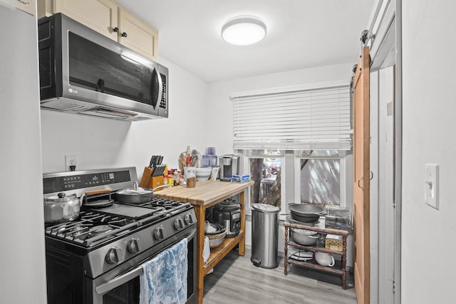 1329 Central St, Oshkosh, WI 54901 - kitchen featuring stainless steel appliances, light wood-style floors, a barn door, and cream cabinetry
