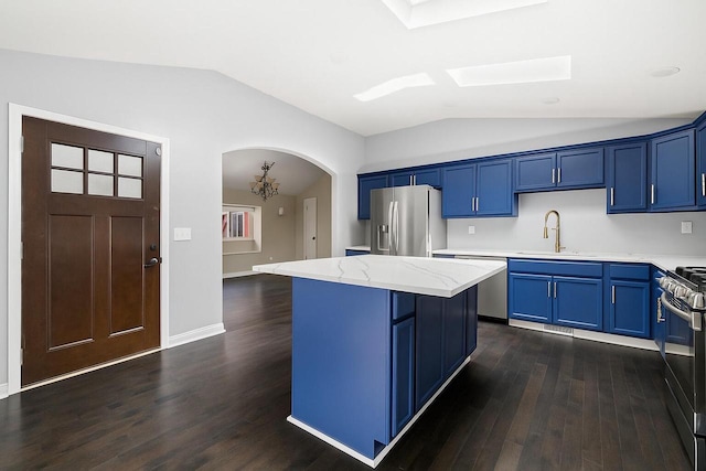 513 61st St, Kenosha, WI 53143 - kitchen featuring stainless steel appliances, blue cabinetry, vaulted ceiling, and dark wood-style floors