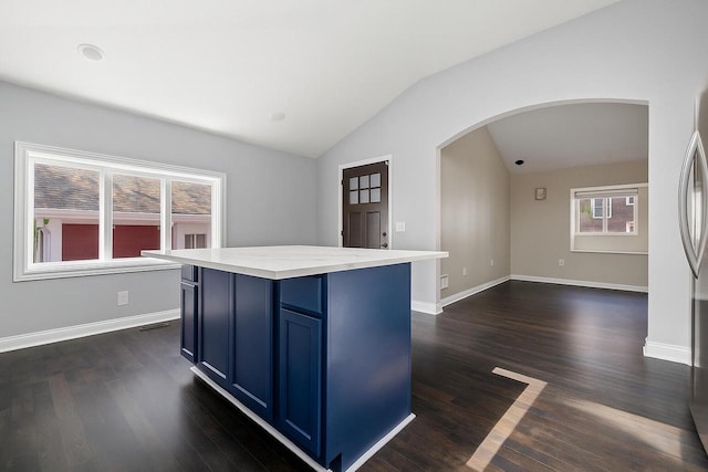 513 61st St, Kenosha, WI 53143 - kitchen with blue cabinetry, arched walkways, vaulted ceiling, light countertops, and dark wood-style flooring