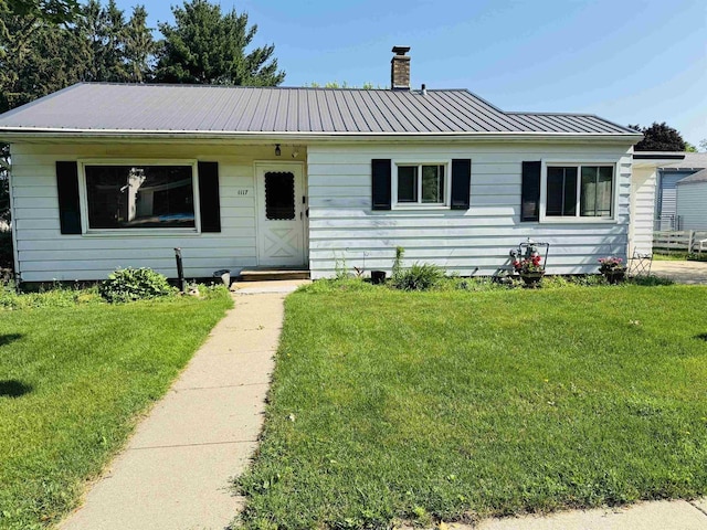 1117 21st St, Monroe, WI 53566 - view of front of house with a chimney, a front yard, and a metal roof