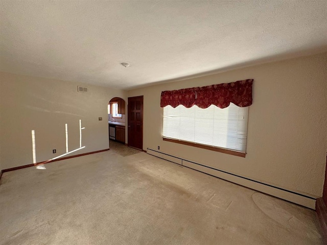 1117 21st St, Monroe, WI 53566 - empty room with arched walkways, a baseboard radiator, light carpet, and a textured ceiling