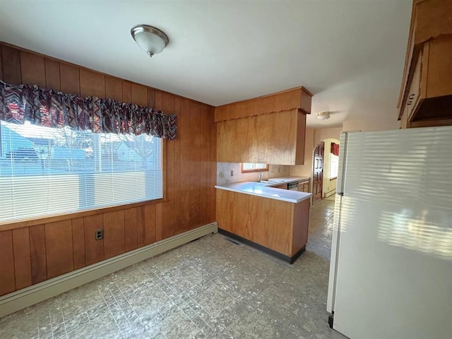1117 21st St, Monroe, WI 53566 - kitchen with light floors, a peninsula, baseboard heating, wooden walls, and light countertops