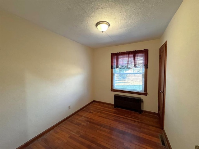 1117 21st St, Monroe, WI 53566 - empty room featuring wood finished floors, a textured ceiling, and radiator heating unit