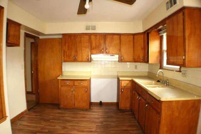 4228 N 52nd St, Milwaukee, WI 53216 - kitchen with under cabinet range hood, brown cabinets, tasteful backsplash, and dark wood-style floors