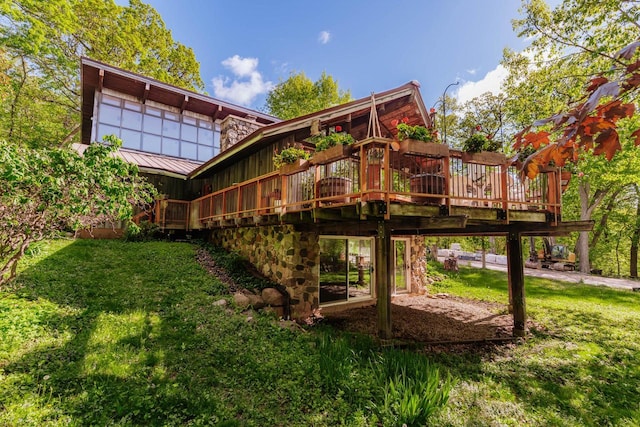 W296N2978 Franciscan Rd, Pewaukee, WI 53072 - back of property featuring a lawn, a standing seam roof, a deck, stone siding, and a metal roof