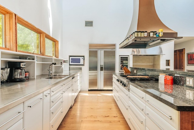 W296N2978 Franciscan Rd, Pewaukee, WI 53072 - kitchen with stainless steel appliances, a towering ceiling, light wood-type flooring, white cabinetry, and beverage cooler