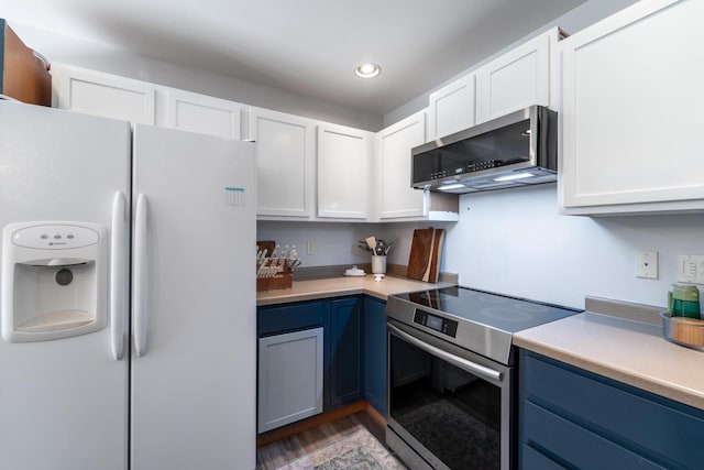 6615 Cavin Dr, Wausau, WI 54401 - kitchen featuring appliances with stainless steel finishes, blue cabinets, light countertops, white cabinets, and recessed lighting