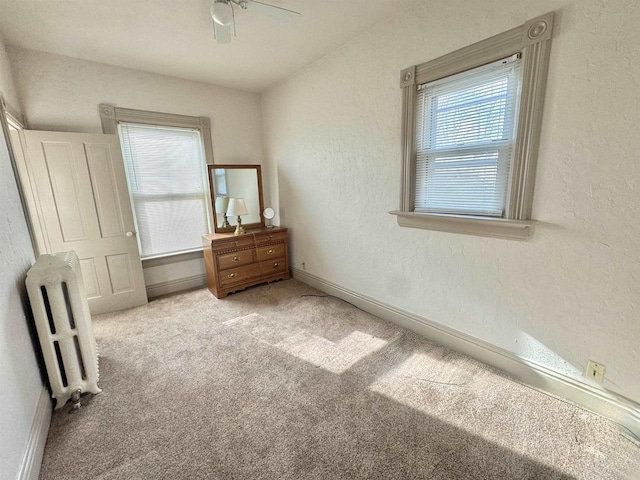 195 E Park Ave, Berlin, WI 54923 - carpeted bedroom featuring radiator heating unit, multiple windows, a ceiling fan, and a textured wall