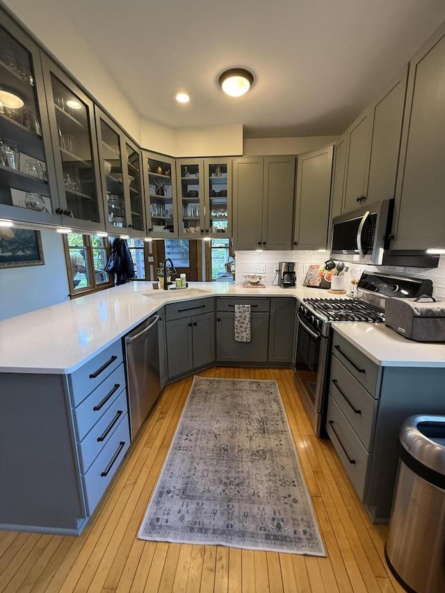 2505 Robinsdale Ave, La Crosse, WI 54601 - kitchen with stainless steel appliances, light wood-style floors, gray cabinets, backsplash, and light countertops