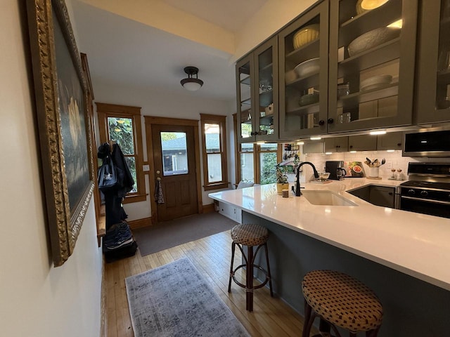 2505 Robinsdale Ave, La Crosse, WI 54601 - kitchen featuring gas range oven, stainless steel microwave, light countertops, a breakfast bar area, and light wood finished floors