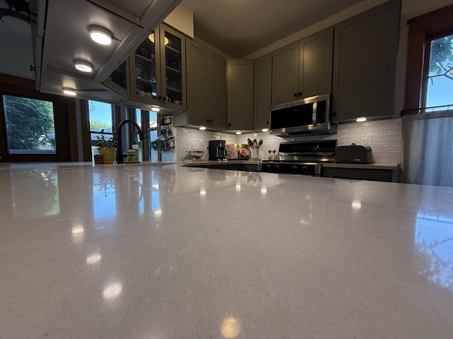 2505 Robinsdale Ave, La Crosse, WI 54601 - kitchen featuring stainless steel microwave, range with electric stovetop, decorative backsplash, and glass insert cabinets