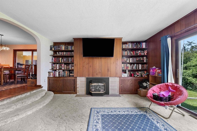 W4976 Pinewood Ln, Merrill, WI 54452 - carpeted living area featuring wooden walls, a textured ceiling, arched walkways, and built in shelves