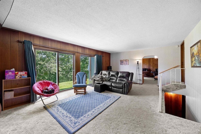 W4976 Pinewood Ln, Merrill, WI 54452 - carpeted living room with arched walkways, a textured ceiling, and wooden walls