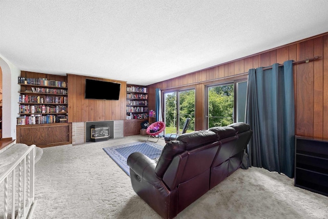 W4976 Pinewood Ln, Merrill, WI 54452 - carpeted living area featuring wooden walls, a textured ceiling, a fireplace, built in shelves, and arched walkways