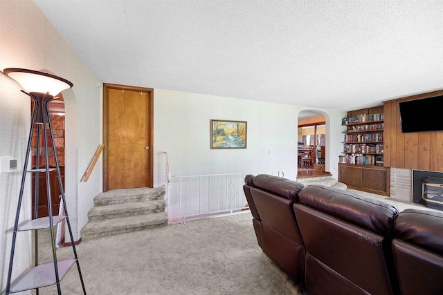 W4976 Pinewood Ln, Merrill, WI 54452 - living room featuring arched walkways, carpet, a textured ceiling, built in features, and stairway