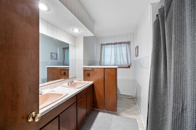 W4976 Pinewood Ln, Merrill, WI 54452 - full bathroom featuring tile walls, double vanity, wallpapered walls, a shower with shower curtain, and tile patterned floors