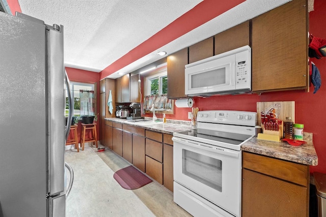 W4976 Pinewood Ln, Merrill, WI 54452 - kitchen with white appliances, brown cabinets, and a textured ceiling