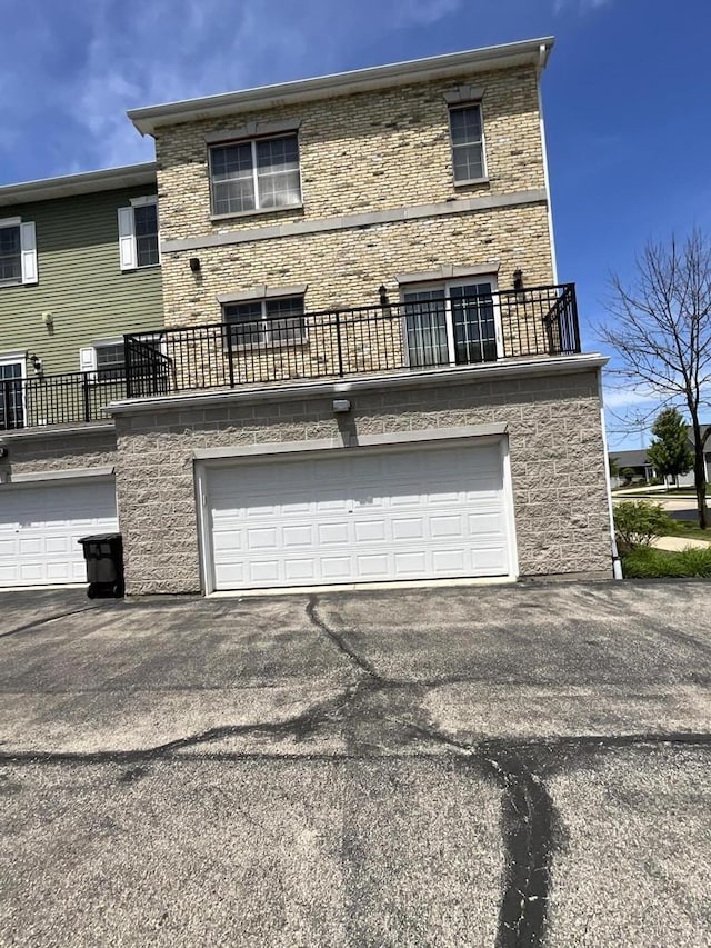 7918 Fredricksburg Ct Unit 101, Bristol, WI 53104 - back of house featuring a balcony, an attached garage, asphalt driveway, and brick siding