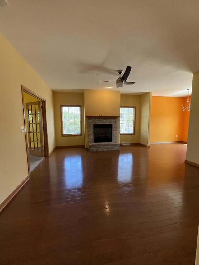 7918 Fredricksburg Ct Unit 101, Bristol, WI 53104 - unfurnished living room with dark wood-style flooring, a fireplace, a chandelier, and ceiling fan