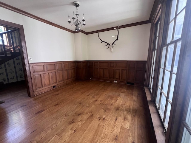 918 Fulton St, Wausau, WI 54403 - unfurnished dining area with light wood-style flooring, crown molding, wainscoting, a chandelier, and a decorative wall