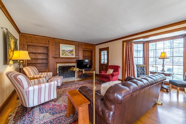 918 Fulton St, Wausau, WI 54403 - living room featuring ornamental molding, light wood-style floors, a tile fireplace, wooden walls, and built in shelves