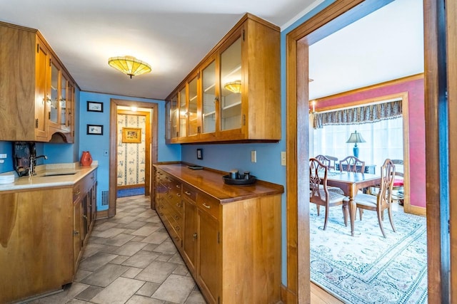 918 Fulton St, Wausau, WI 54403 - kitchen featuring brown cabinetry, glass insert cabinets, and stone finish floors