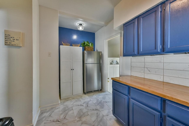 2710 W Fairmount Ave, Milwaukee, WI 53209 - kitchen featuring freestanding refrigerator, wood counters, blue cabinets, and light marble finish flooring