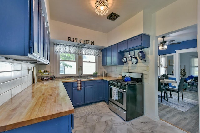 2710 W Fairmount Ave, Milwaukee, WI 53209 - kitchen featuring stainless steel range with gas stovetop, blue cabinets, butcher block countertops, ceiling fan, and backsplash