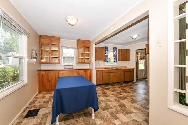 6148 N 38th St, Milwaukee, WI 53209 - kitchen featuring brown cabinetry, stone finish floors, open shelves, plenty of natural light, and ornamental molding