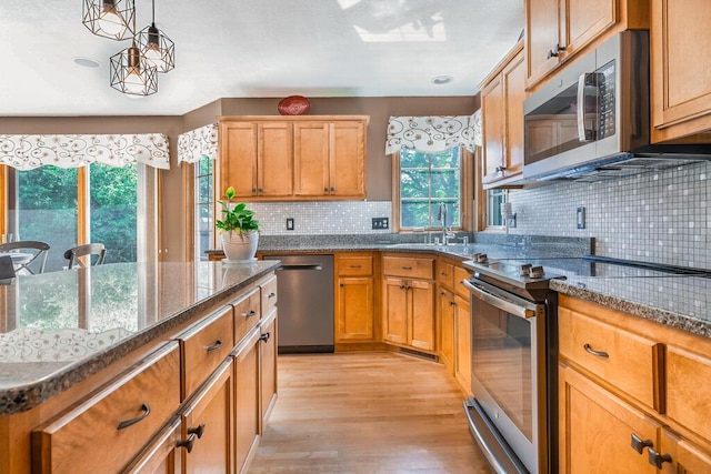4474 N 107th St, Wauwatosa, WI 53225 - kitchen featuring stainless steel appliances, light wood finished floors, decorative backsplash, hanging light fixtures, and dark stone countertops
