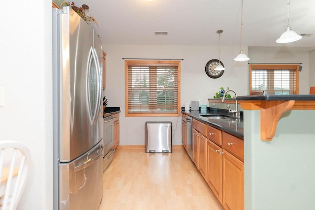 W162S7013 Olive Cir, Muskego, WI 53150 - kitchen featuring appliances with stainless steel finishes, light wood-style flooring, decorative light fixtures, a peninsula, and a kitchen bar