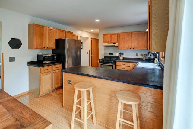 130 W Windsor Ave, Cottage Grove, WI 53527 - kitchen with appliances with stainless steel finishes, under cabinet range hood, dark countertops, light wood finished floors, and recessed lighting