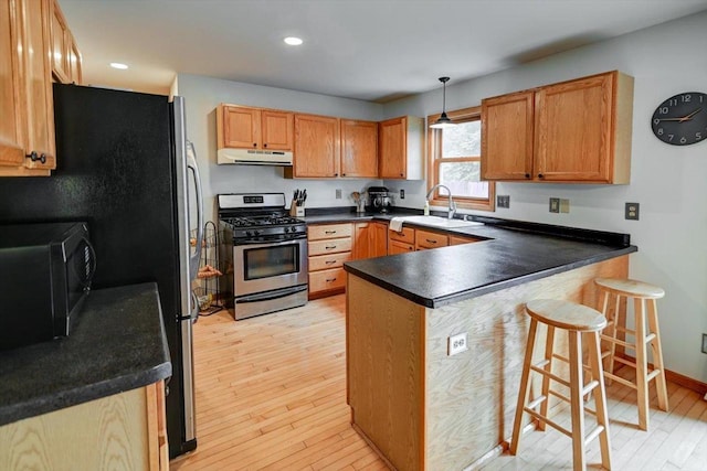 130 W Windsor Ave, Cottage Grove, WI 53527 - kitchen with gas range, under cabinet range hood, a peninsula, black microwave, and light wood-style flooring