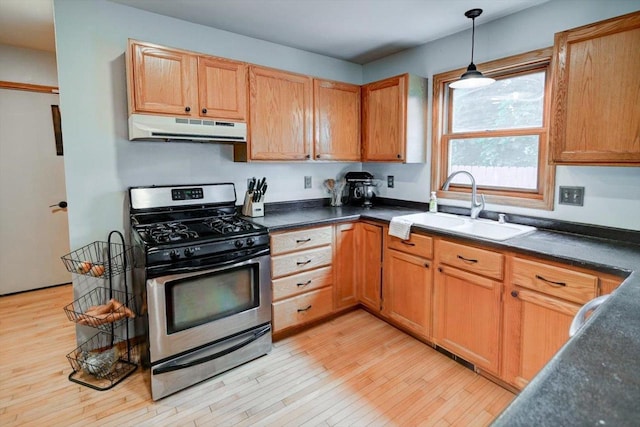 130 W Windsor Ave, Cottage Grove, WI 53527 - kitchen featuring under cabinet range hood, stainless steel gas range oven, dark countertops, light wood-style flooring, and hanging light fixtures
